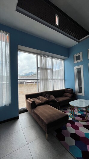 A living room with a brown sofa, a small white table, and a colorful rug.