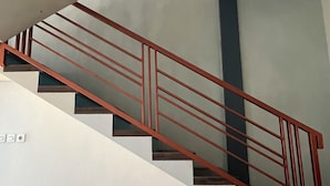 A staircase with a metal railing, white walls, and a blue ceiling. - Rees Cabin & Homestay (Dieng Kulon)