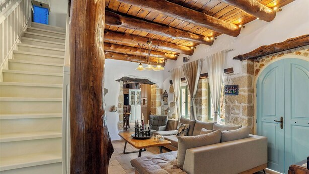 A cozy living room with a sofa, a coffee table, and a stone wall. - Villa Cava – Villa with a private pool in Crete (Xirostérnion)