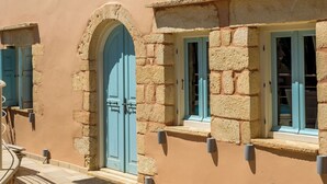 A building with a stone facade, a large arched door, and multiple windows with shutters. - Villa Cava – Villa with a private pool in Crete (Xirostérnion)
