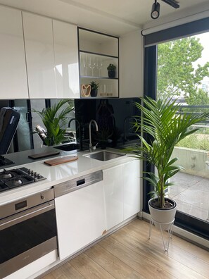 Una cocina moderna con armarios blancos, estufa integrada y un amplio ventanal con vistas al exterior.