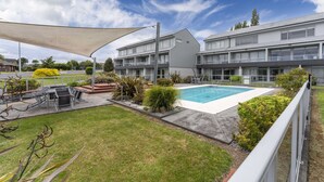 A hotel with a swimming pool, outdoor seating, and a covered patio area. - Lake Terrace Apartment (Taupō)