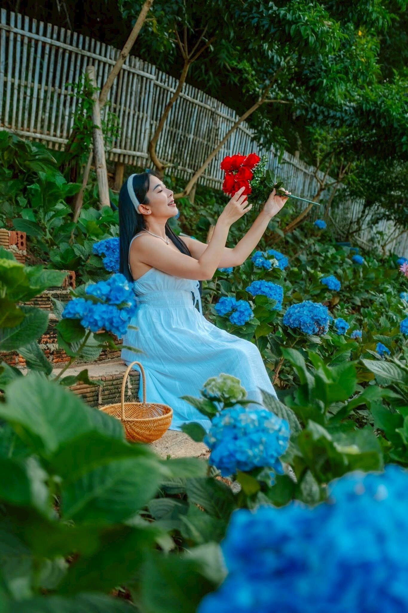 Eine Person sitzt auf einer Bank, umgeben von blauen Hortensienblüten.