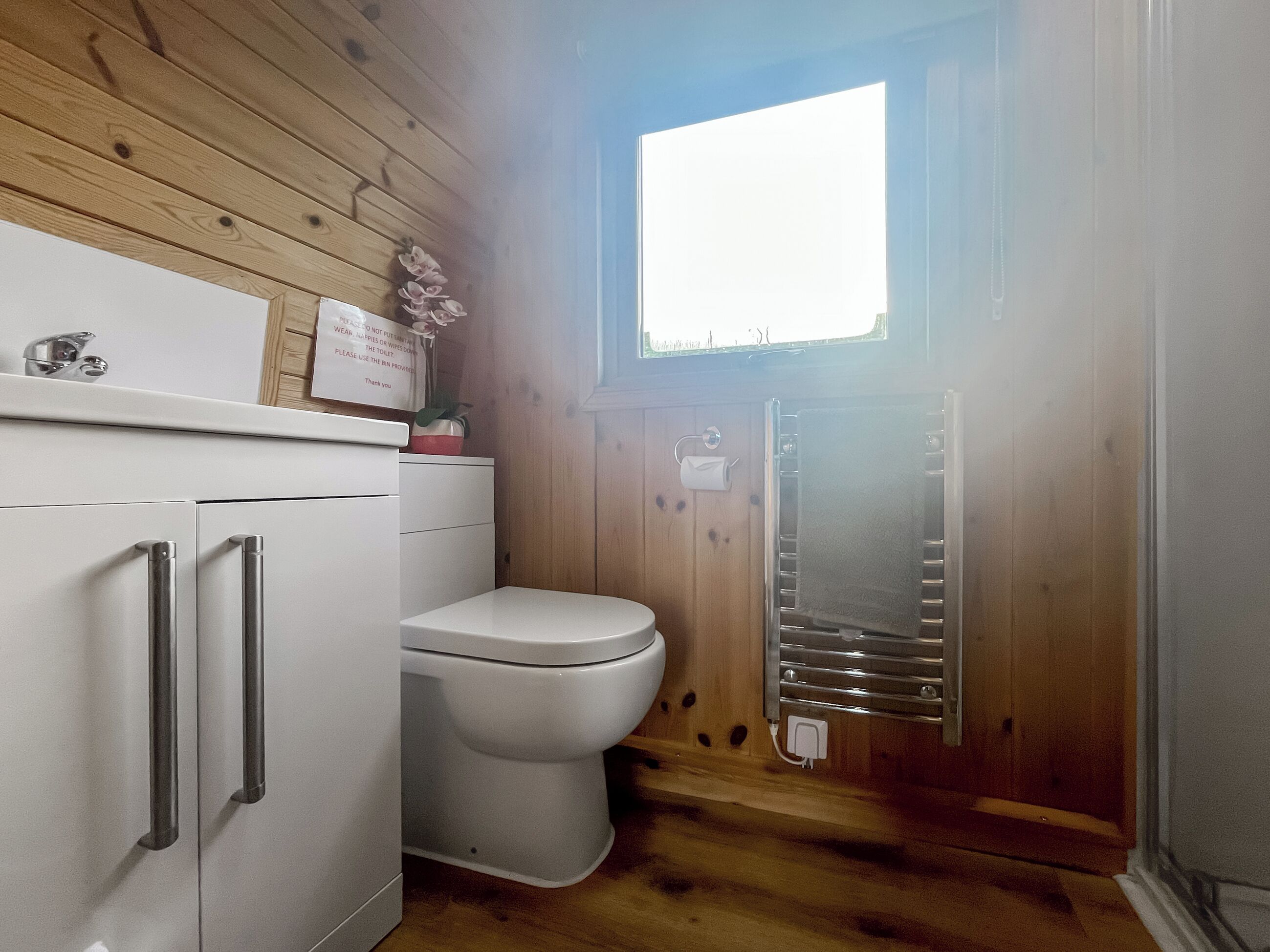 A compact bathroom with a toilet, a white cabinet with drawers, and a towel rack.