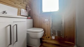 Ein kleines Badezimmer mit Toilette, einem weißen Schrank mit Schubladen und einem Handtuchhalter.