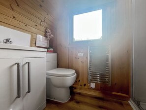 Ett litet badrum med en toalett, ett vitt skåp med lådor och en handduksställning.