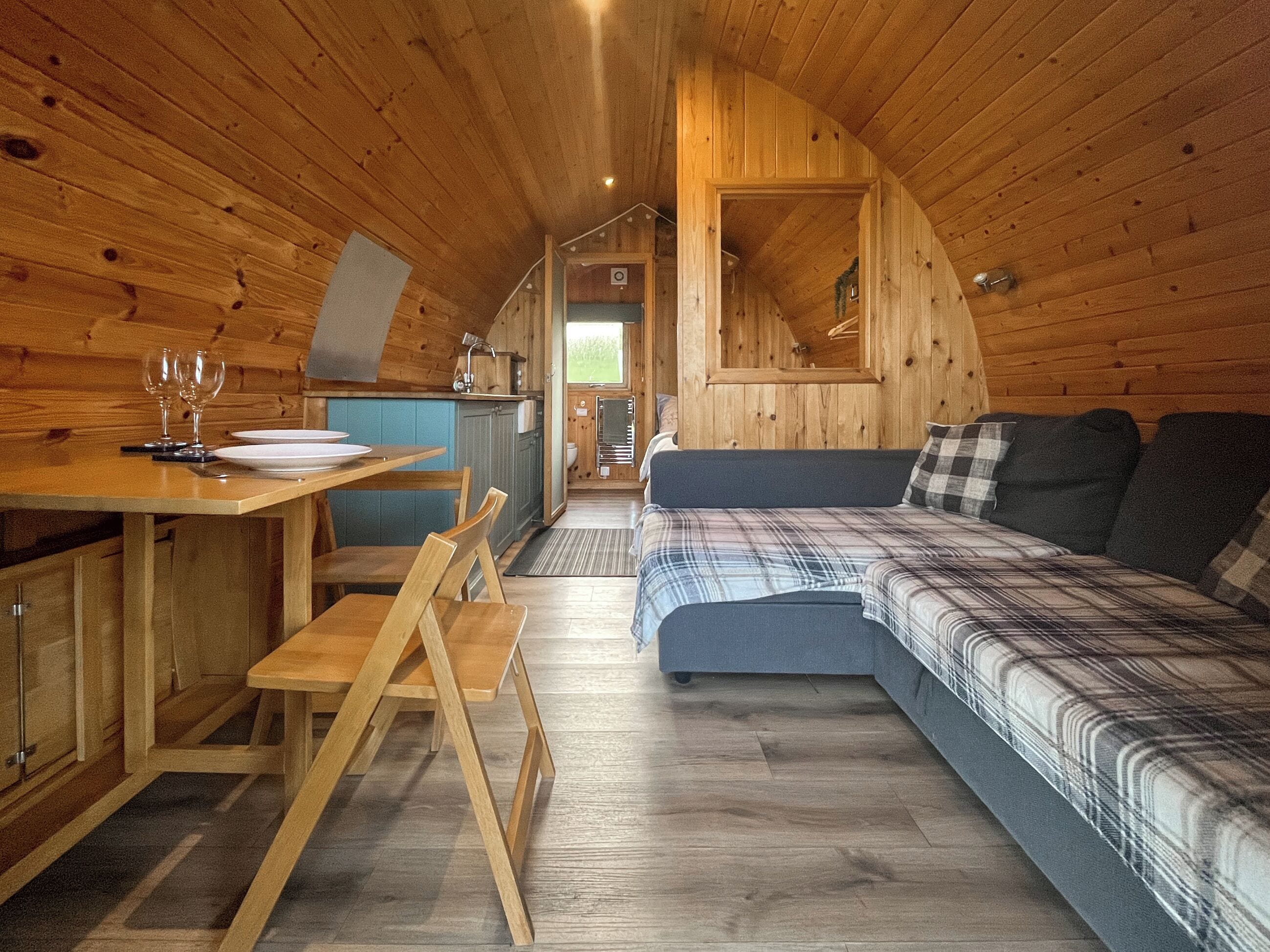 A cozy cabin interior with a dining area, a sofa, and a kitchen.