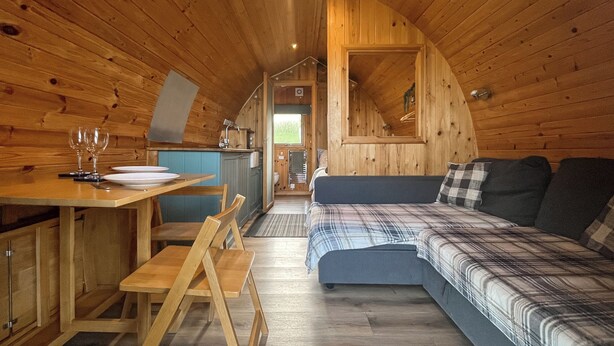 Ein gemütliches Blockhausschlafzimmer mit Essbereich, einer Couch und einer Küche.