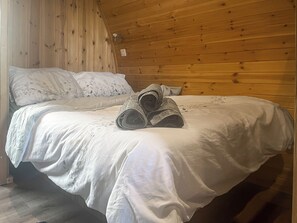 A neatly made bed with white linens and rolled towels in a wooden cabin room. - 1 bedroom accommodation in Dalton-in-Furness (Dalton-in-Furness)