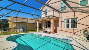 Piscina com água azul cristalina, rodeada por um espaço coberto com mobiliário de exterior.