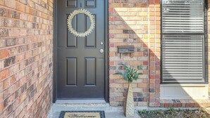 A dark brown front door with a wreath, a potted plant, and a welcome mat. - 1 Mi to LSU, Tiger Stadium! Lovely Home w/ Parking (Baton Rouge)