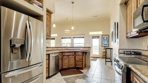 A spacious kitchen with a stainless steel refrigerator, wooden cabinets, a large island, and a gas stove. - Golf, Hike & Stargaze: Quiet Home in Las Cruces (Las Cruces)