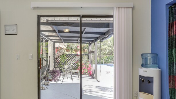 Puerta corrediza de vidrio que da a un patio exterior con dispensador de agua y vistas a un jardín.
