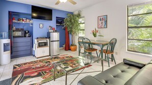 Una cocina compacta con electrodomésticos modernos, un comedor con mesa de vidrio y una zona de estar acogedora con sofá.