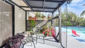 Un patio cubierto con piscina, mobiliario exterior y plantas en macetas.