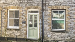 A stone building with a green door, multiple windows, and a visible sign reading "KENWITH Church Street". - 2 bedroom accommodation in Looe (Looe)