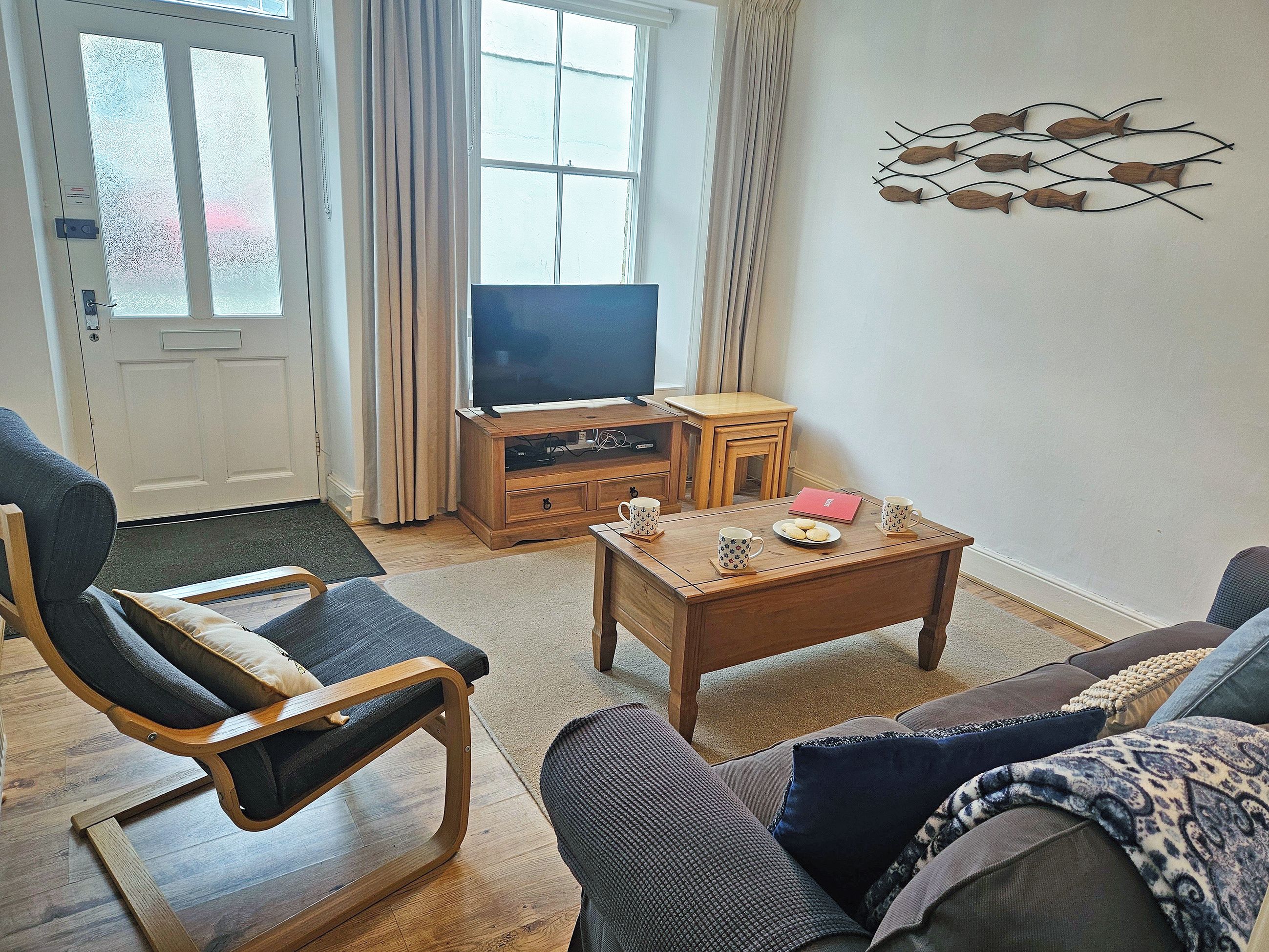A living room with a sofa, a wooden coffee table, a TV, and a wall art piece.