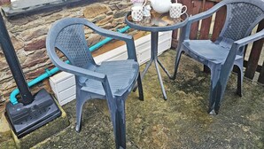 Two grey plastic chairs with a small table between them, a white teapot, and a white mug with anchor designs. - 2 bedroom accommodation in Looe (Looe)