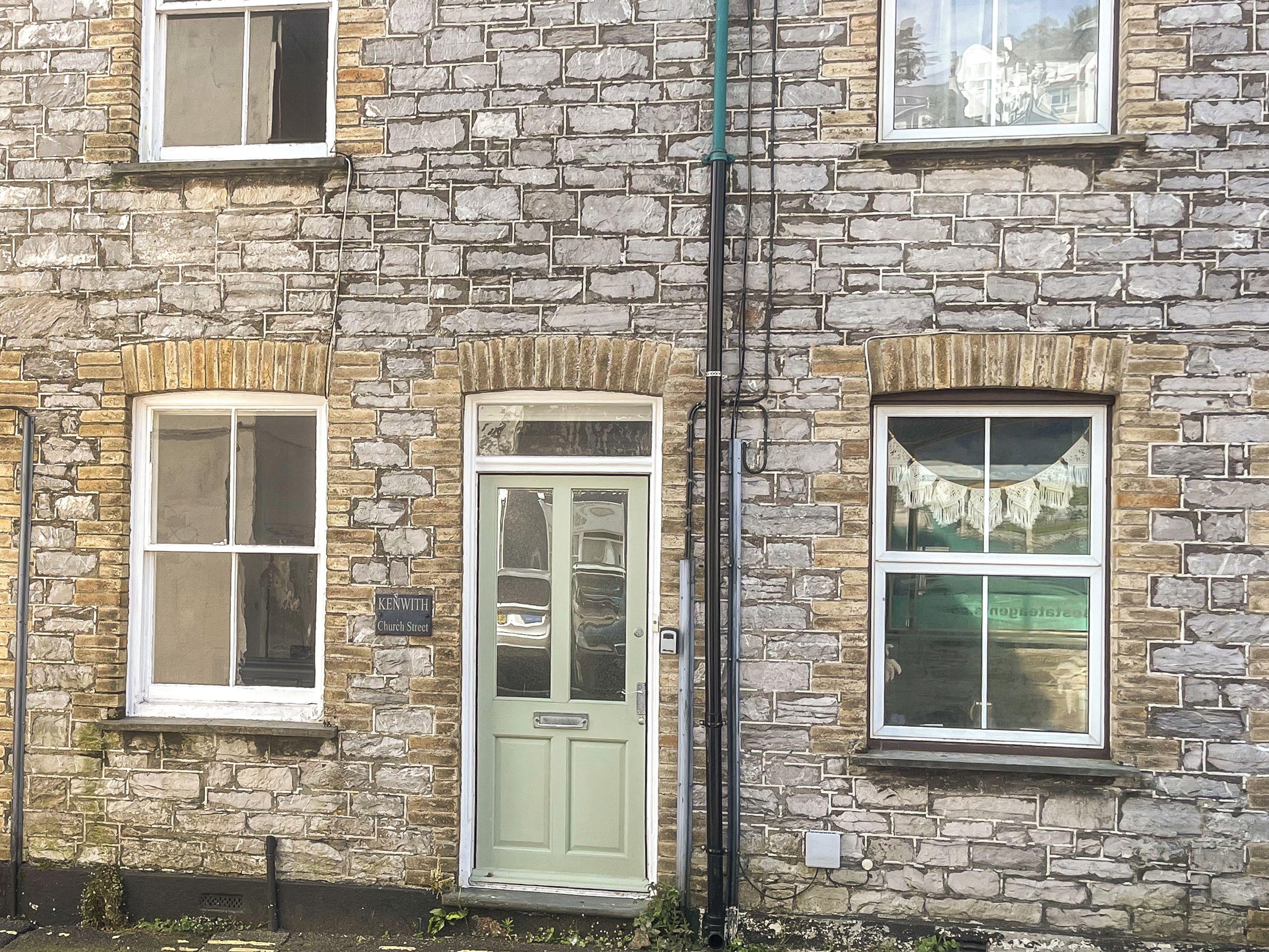 A stone building with a green door, multiple windows, and a visible sign reading "KENWITH Church Street".