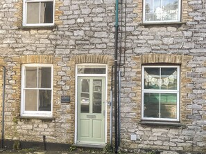 A stone building with a green door, multiple windows, and a visible sign reading "KENWITH Church Street". - 2 bedroom accommodation in Looe (Looe)