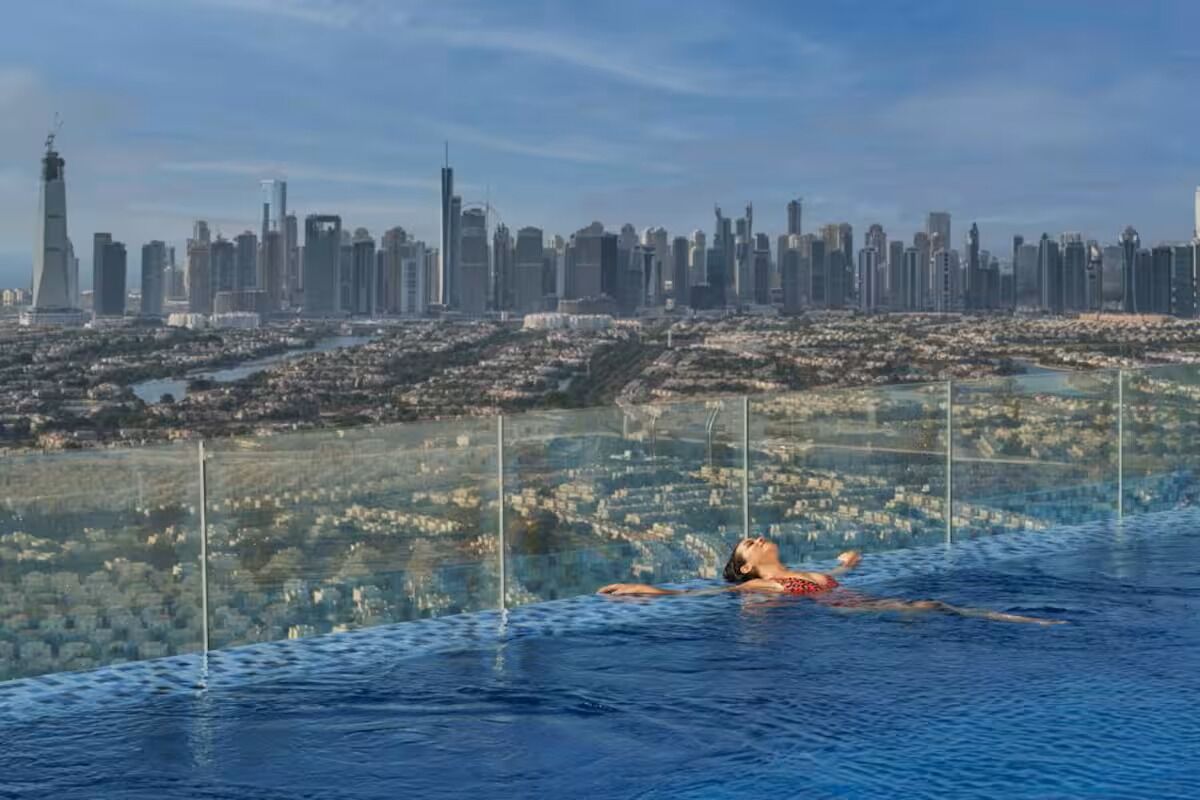 A person swimming in a pool with a cityscape in the background.
