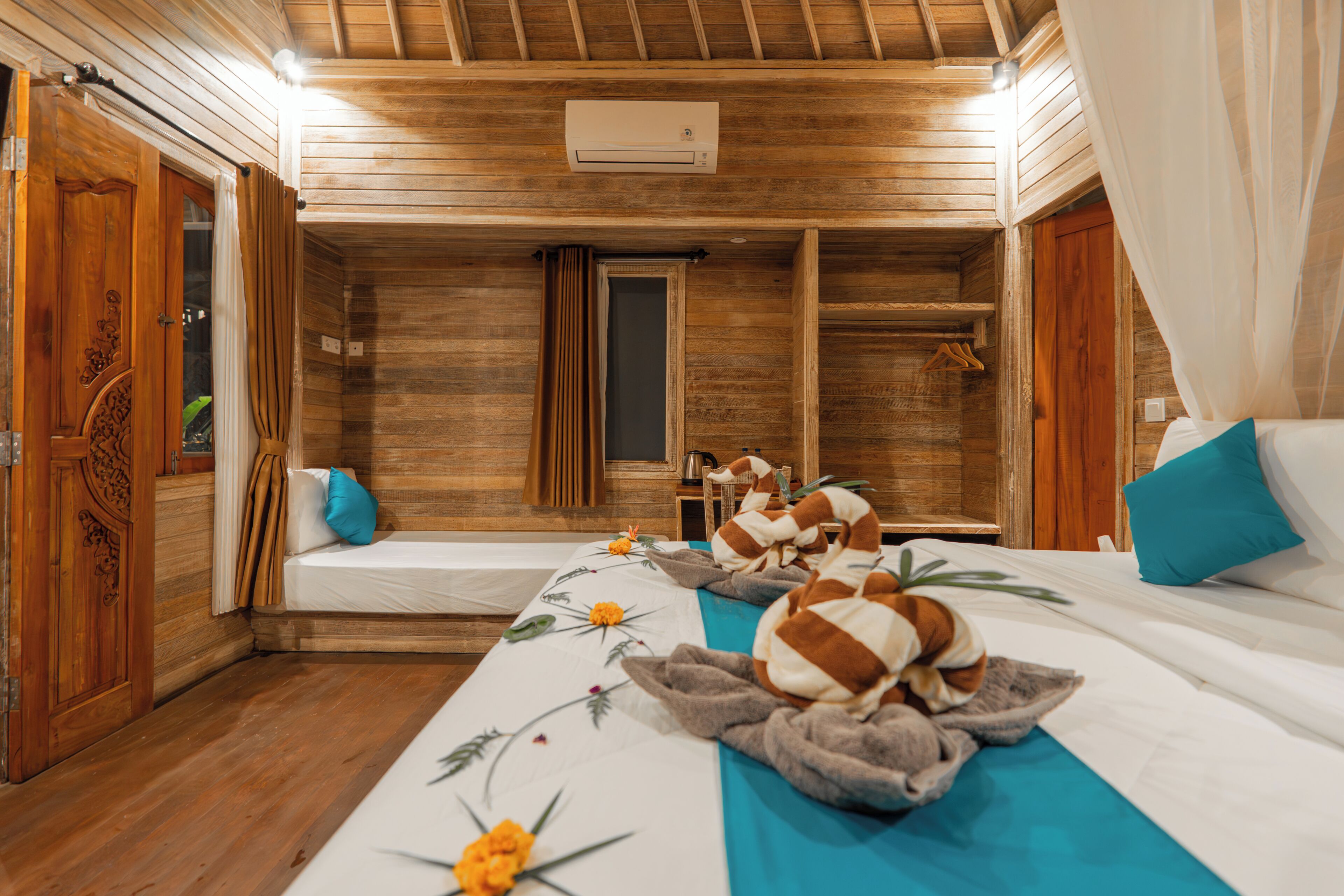 A wooden room with two beds, a mirror, a window, and an air conditioning unit.