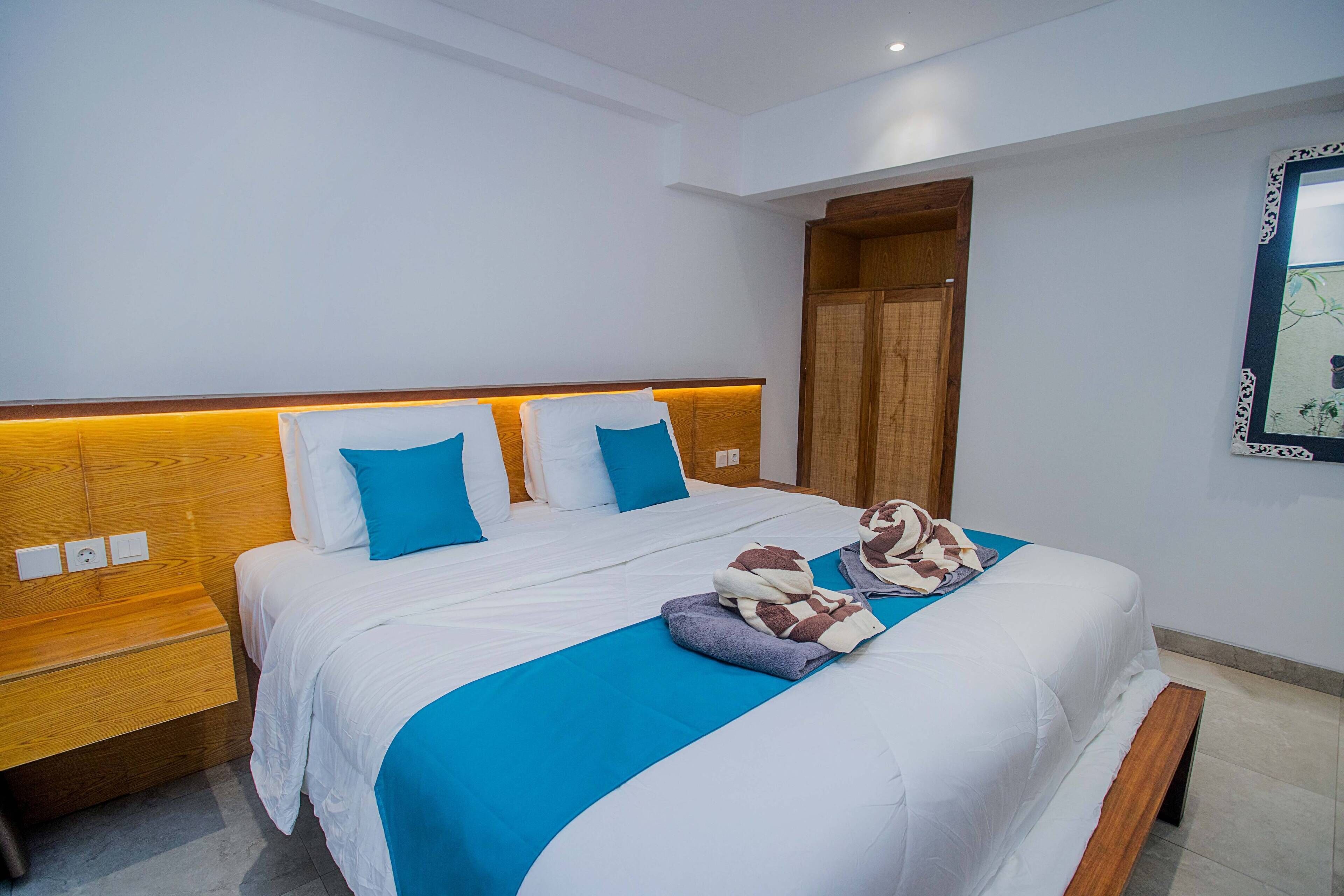 Habitación de hotel con una cama grande, cabecero de madera y una pared de acento azul.