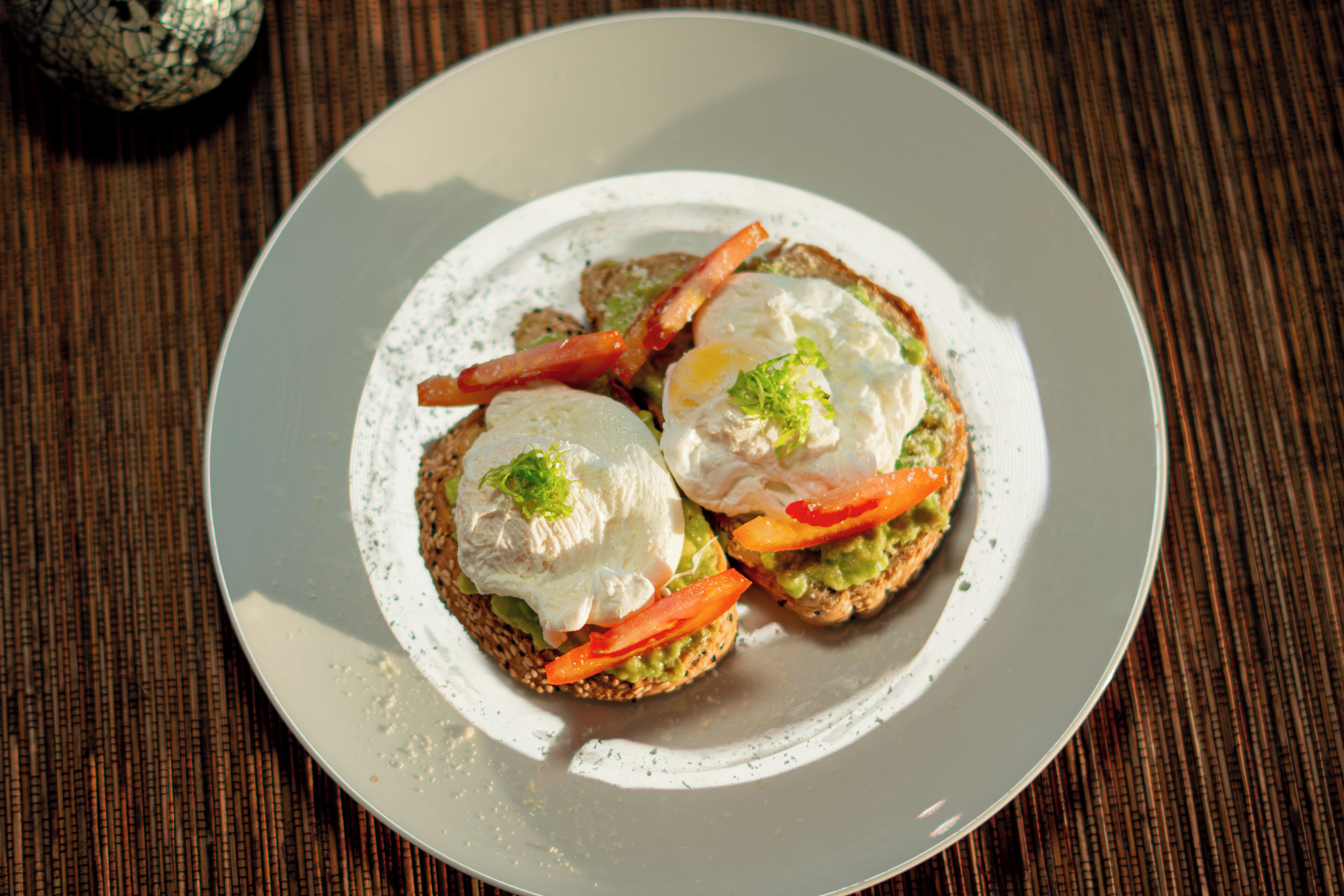 A plate with two open-faced sandwiches, each topped with a poached egg and slices of tomato.