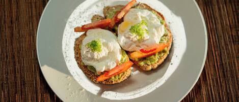 A plate with two open-faced sandwiches, each topped with a poached egg and slices of tomato.