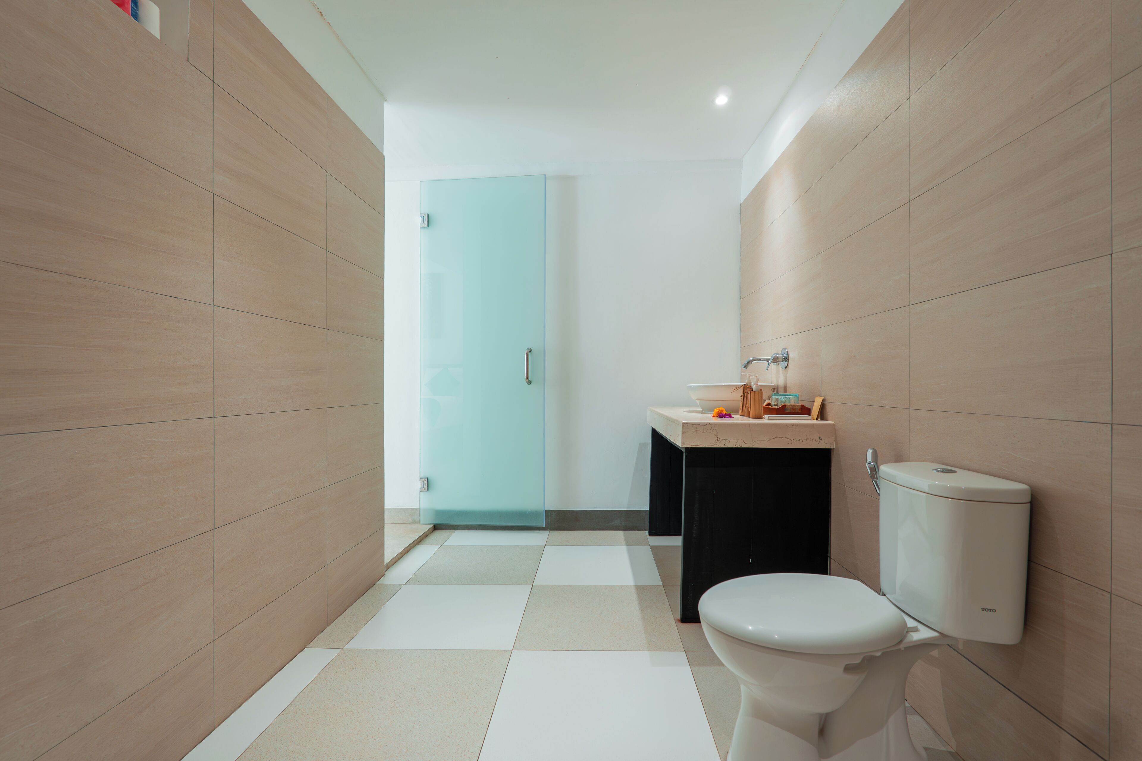 A modern bathroom with a toilet, sink, and glass shower door.
