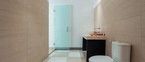 A modern bathroom with a toilet, sink, and glass shower door.