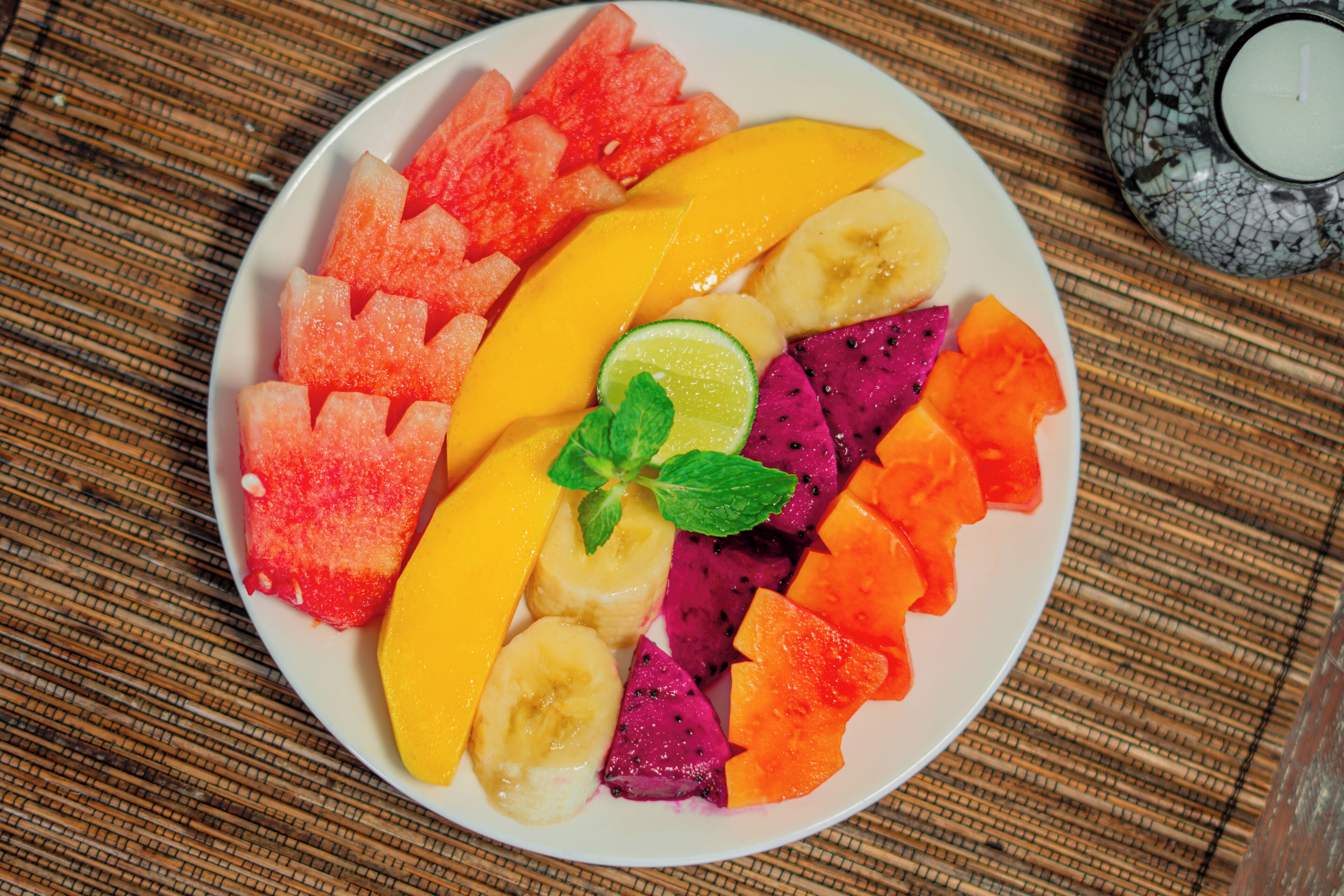 Une assiette remplie d’un assortiment de fruits, posée sur une surface texturée.