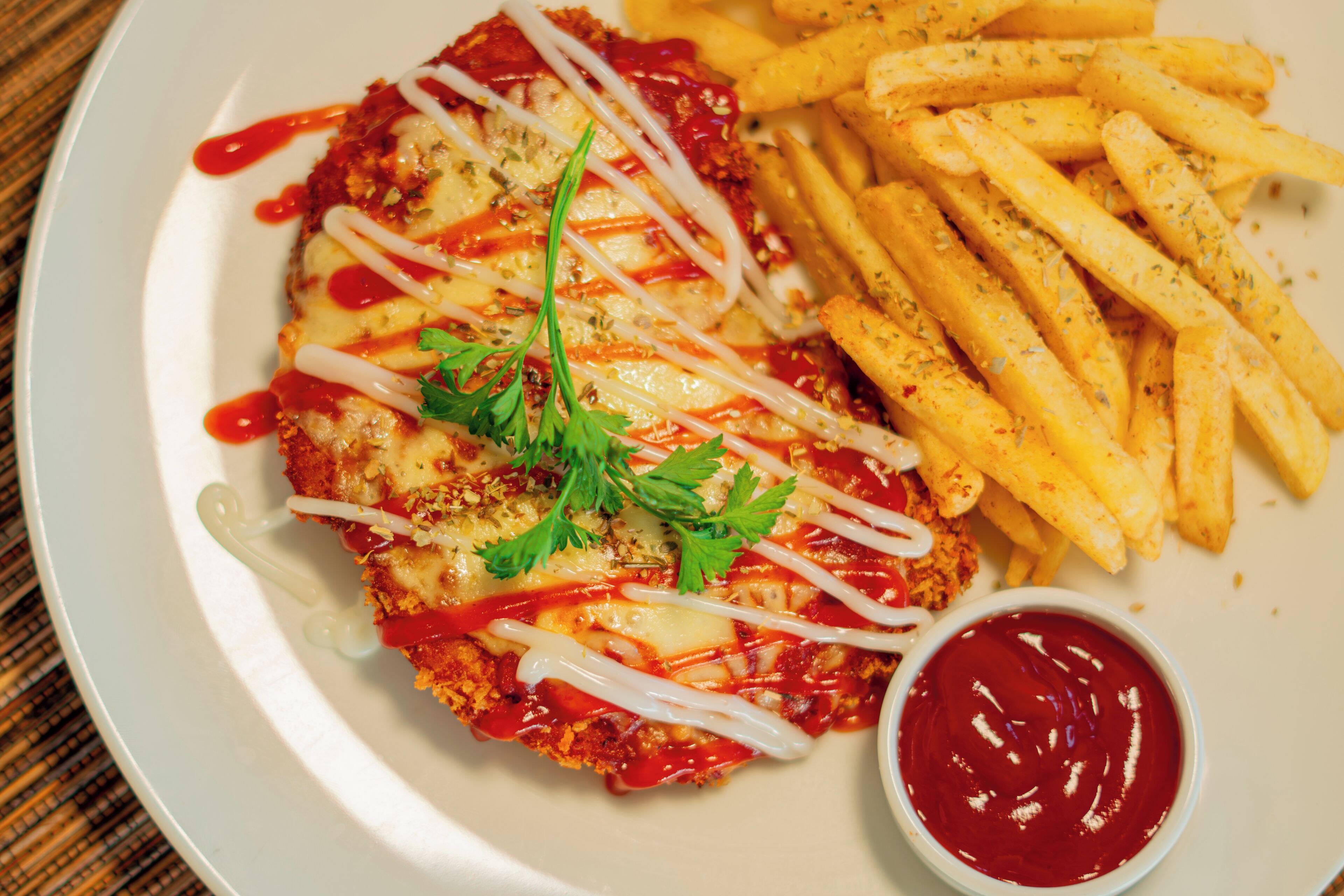 A plate with a breaded and fried cutlet, fries, and a small bowl of ketchup.