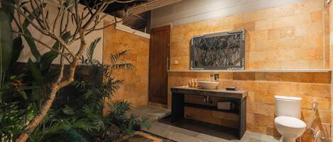 A bathroom with a stone wall, a sink, a toilet, and a shower.