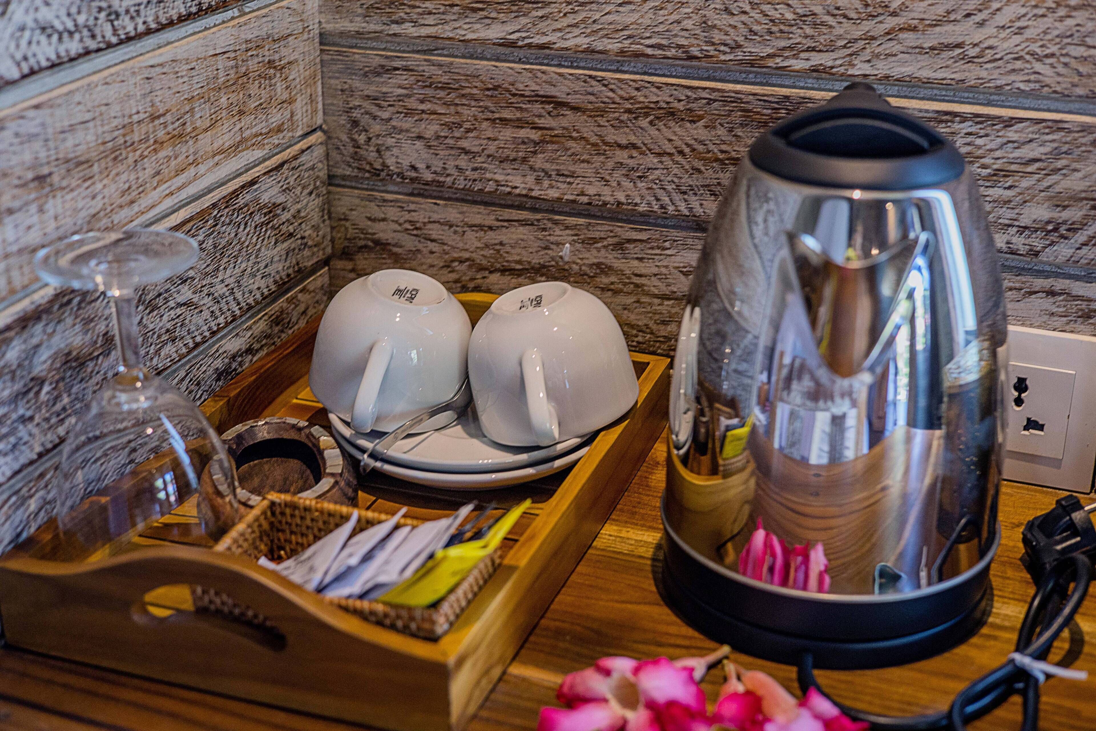 A wooden tray with a kettle, teapots, and a glass.
