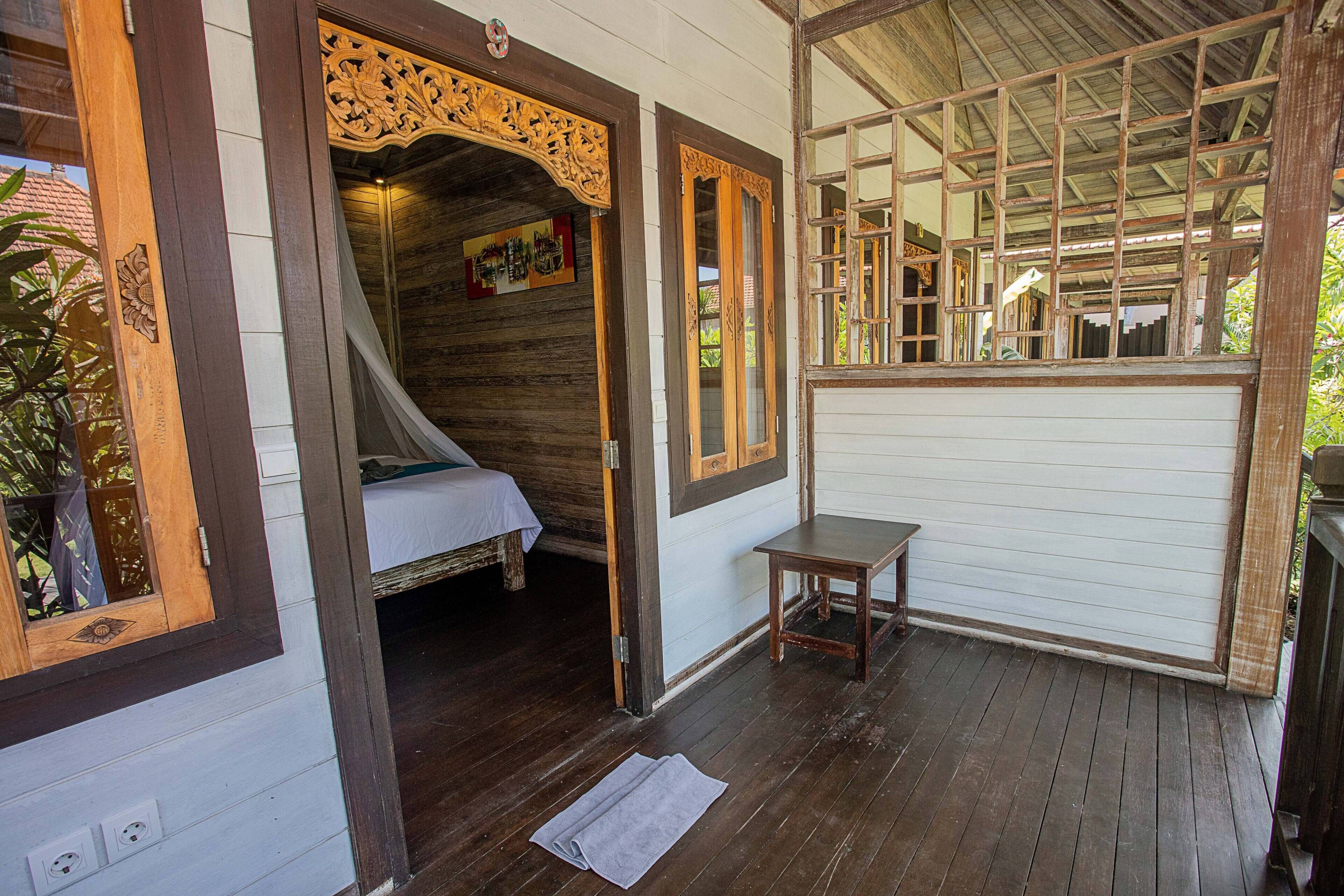 A traditional wooden room with a bed, a small table, and a window with a wooden frame.