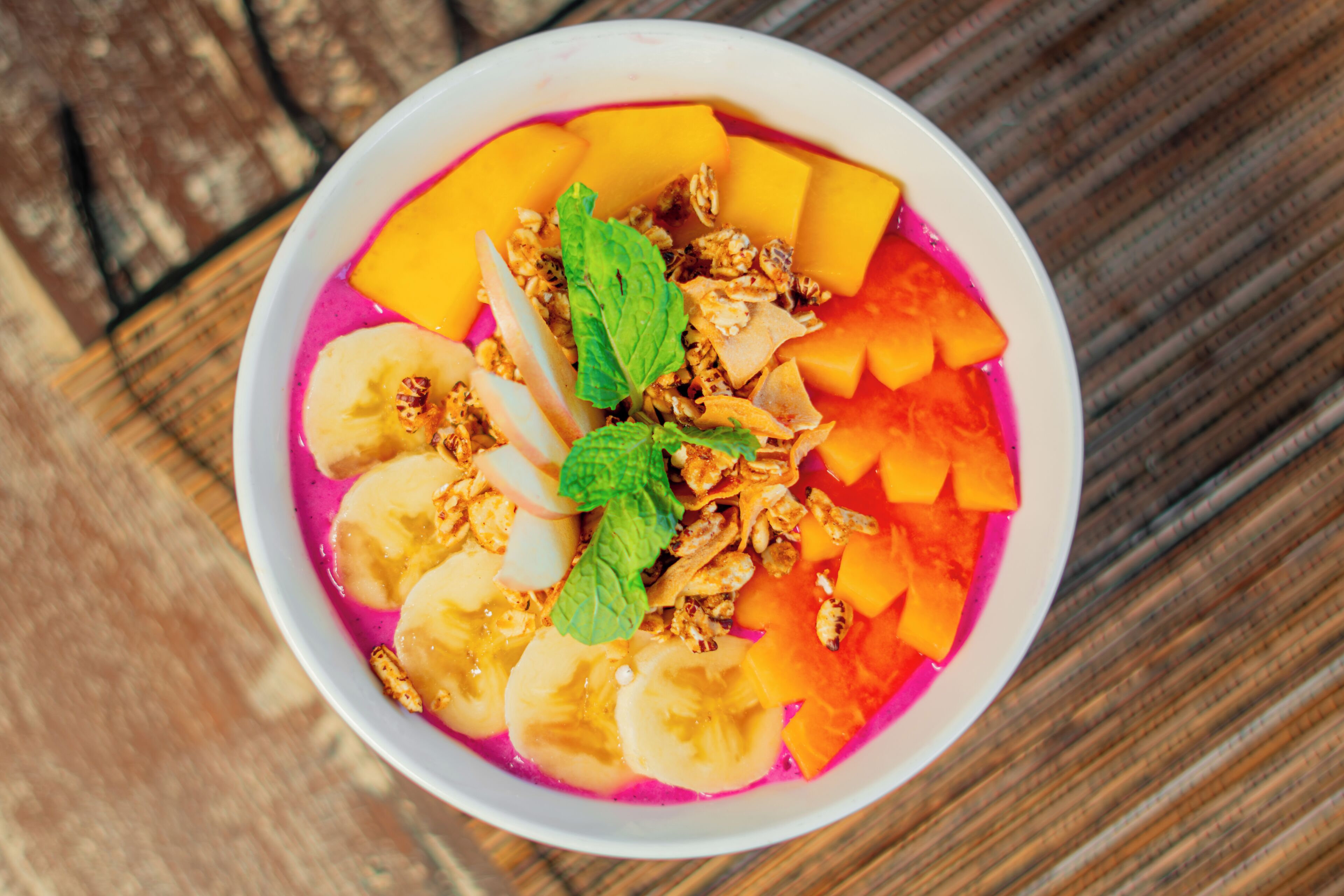 Een fruitsalade met granola en muntblaadjes.