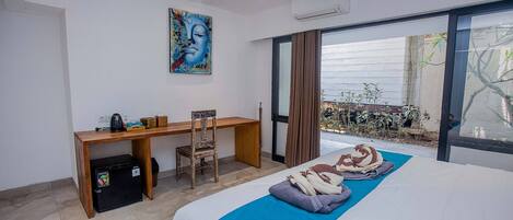 A hotel room with a bed, a desk, a chair, and a small refrigerator.