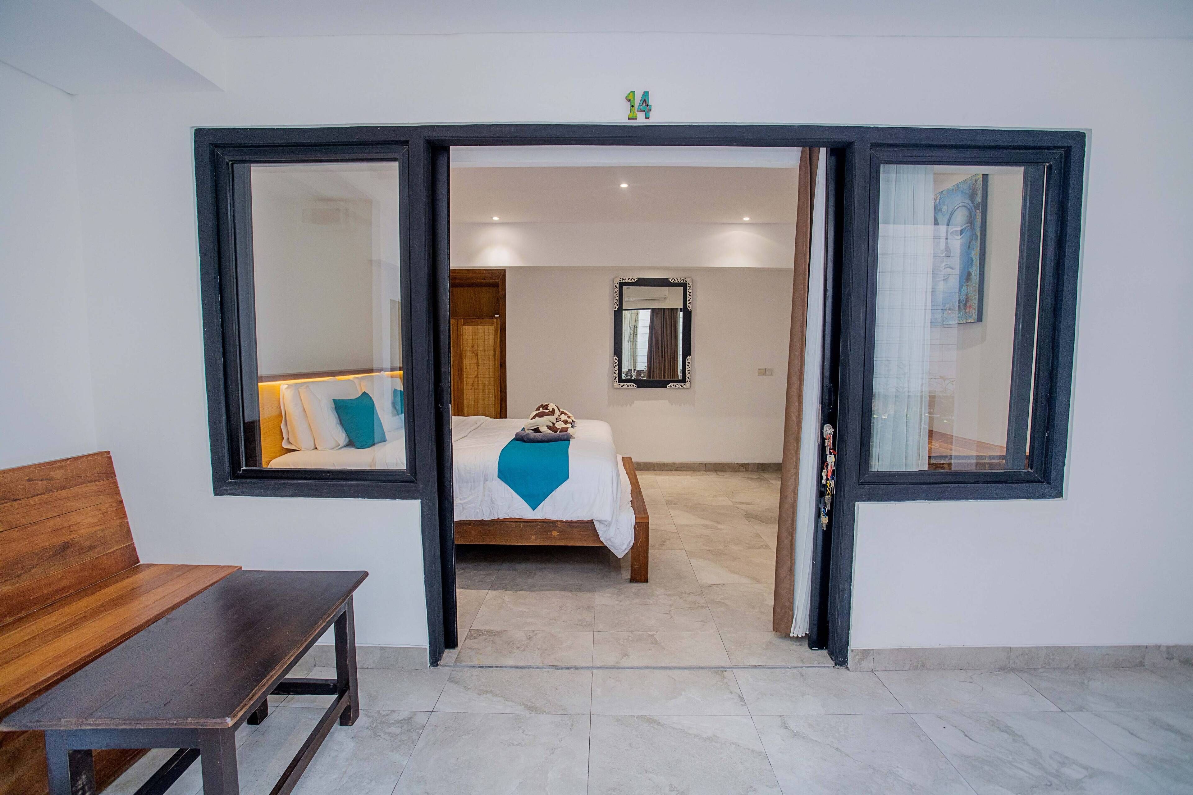 A bedroom with a bed, a bench, and a large window.