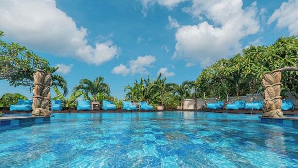 A swimming pool with clear blue water, surrounded by palm trees and lounge chairs. - D’Gume Villas Lembongan by Bali Cabin (Lembongan Island)