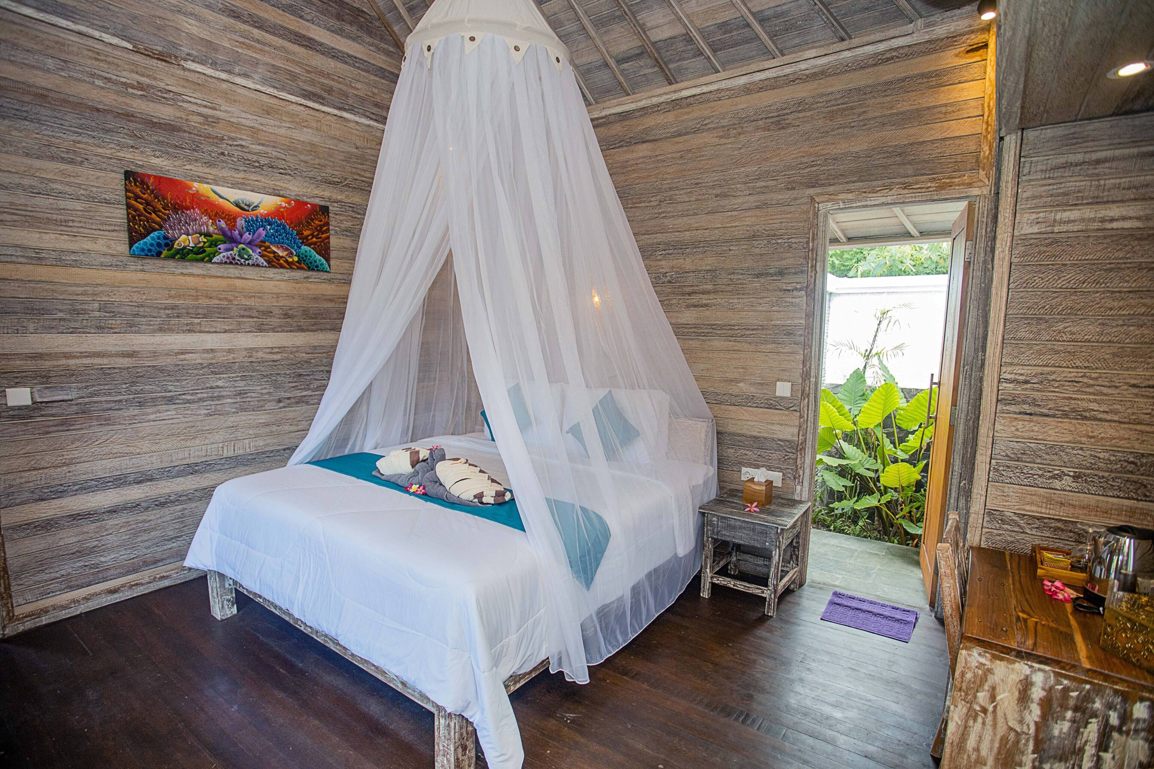 A bedroom with a canopy bed, wooden walls, a small bedside table, and a view of greenery outside.