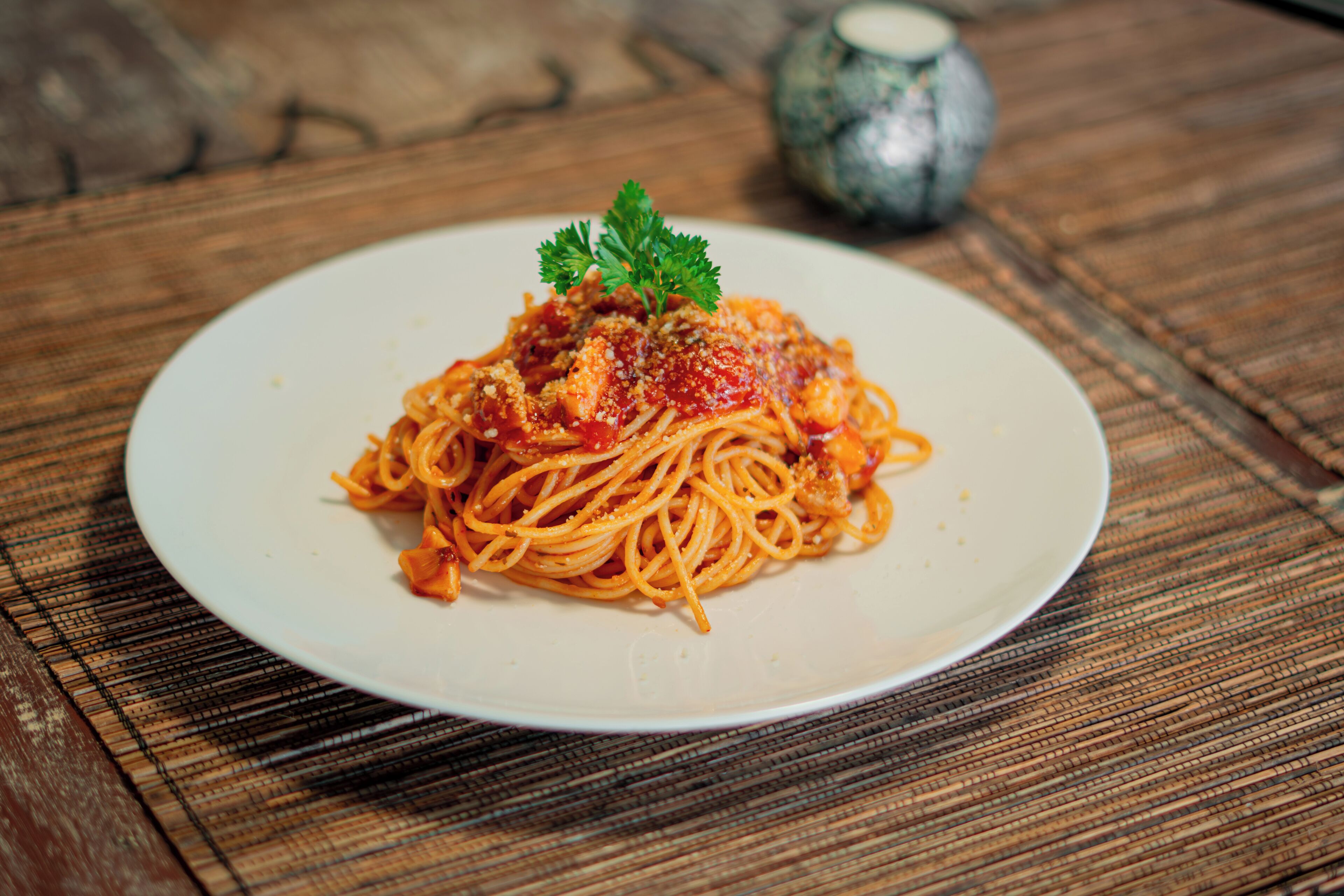 Un plato de espagueti con adorno sobre una mesa de madera.