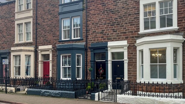 A row of terraced houses with distinct architectural styles, including bay windows and different colored facades. - Lakes and Shores Retreat (Maryport)