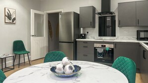 A modern kitchen with a marble table, green chairs, and a Bosch oven. - Lakes and Shores Retreat (Maryport)