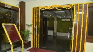 A hotel entrance with a glass door, yellow flower garlands, a welcome sign, and a red carpet. - Aalcajars Inn (Patna)