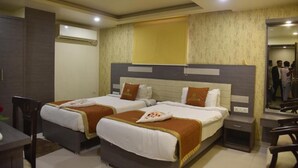 A hotel room with two beds, a desk, and a chair. - Aalcajars Inn (Patna)