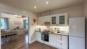 A modern kitchen with white cabinets, a built-in oven, and a refrigerator. - Rookery Farm Holiday Cottage (Bognor Regis)