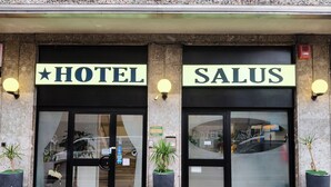 Entrada de hotel com duas grandes portas de vidro, cada uma com uma placa.