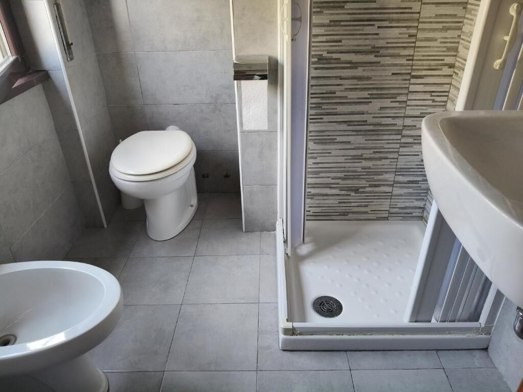 A modern bathroom with a toilet, bidet, and shower area.