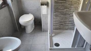 A modern bathroom with a toilet, bidet, and shower area.